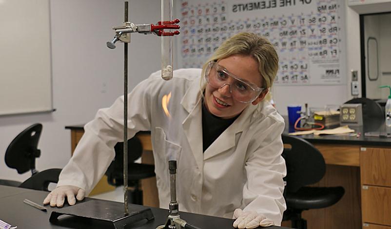 Peyton using a bunsen burner to heat up a substance in a test tube